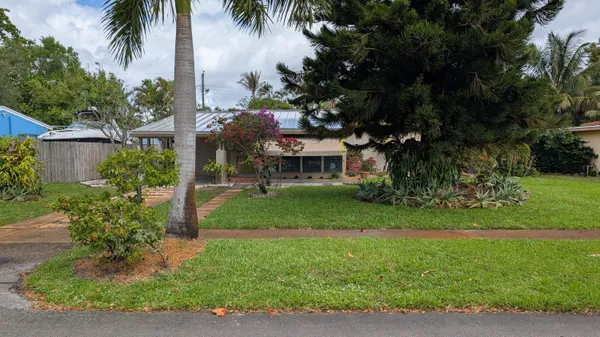 a front view of a house with a garden and trees