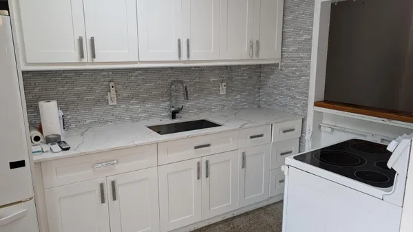 a kitchen with white cabinets and sink