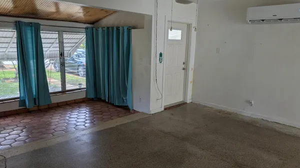 an empty room with windows wooden floor and front door