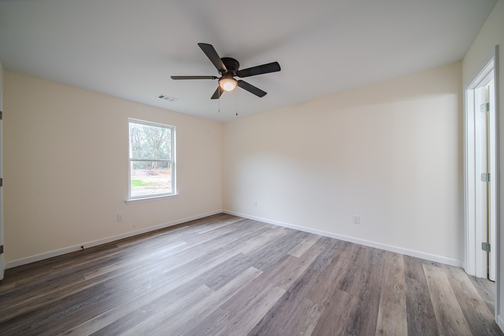 4396 Forrest Road Columbus, GA 31907 - Photo 14 of 24 an empty room with wooden floor a ceiling fan and windows
