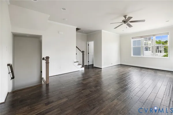 an empty room with wooden floor windows and a ceiling fan