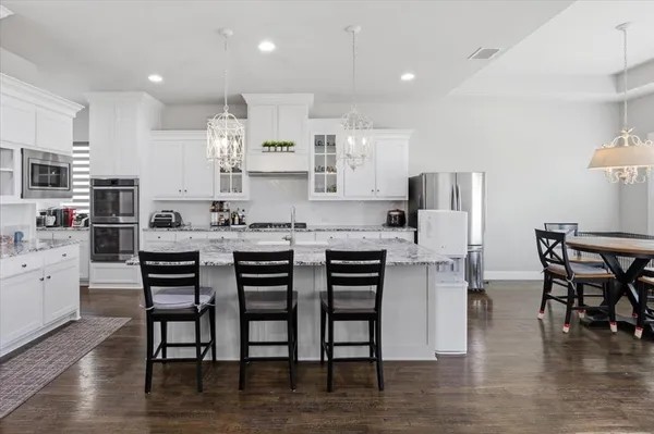 a kitchen with stainless steel appliances kitchen island granite countertop a table chairs and a refrigerator