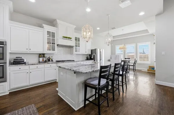 a kitchen with granite countertop a table chairs stove and white cabinets