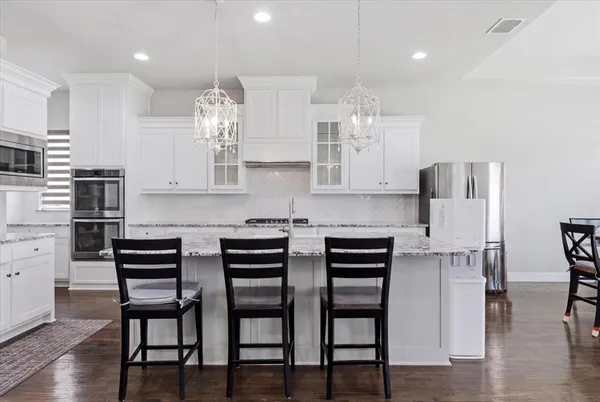 a kitchen with stainless steel appliances a dining table chairs microwave and stove