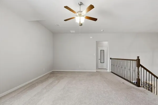 an empty room with chandelier fan and windows