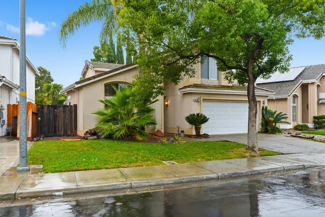 a view of a white house with a yard and plants