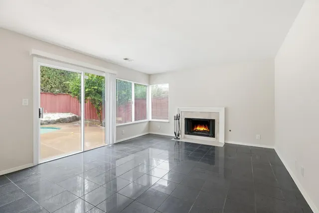 an empty room with floor to ceiling windows and fireplace