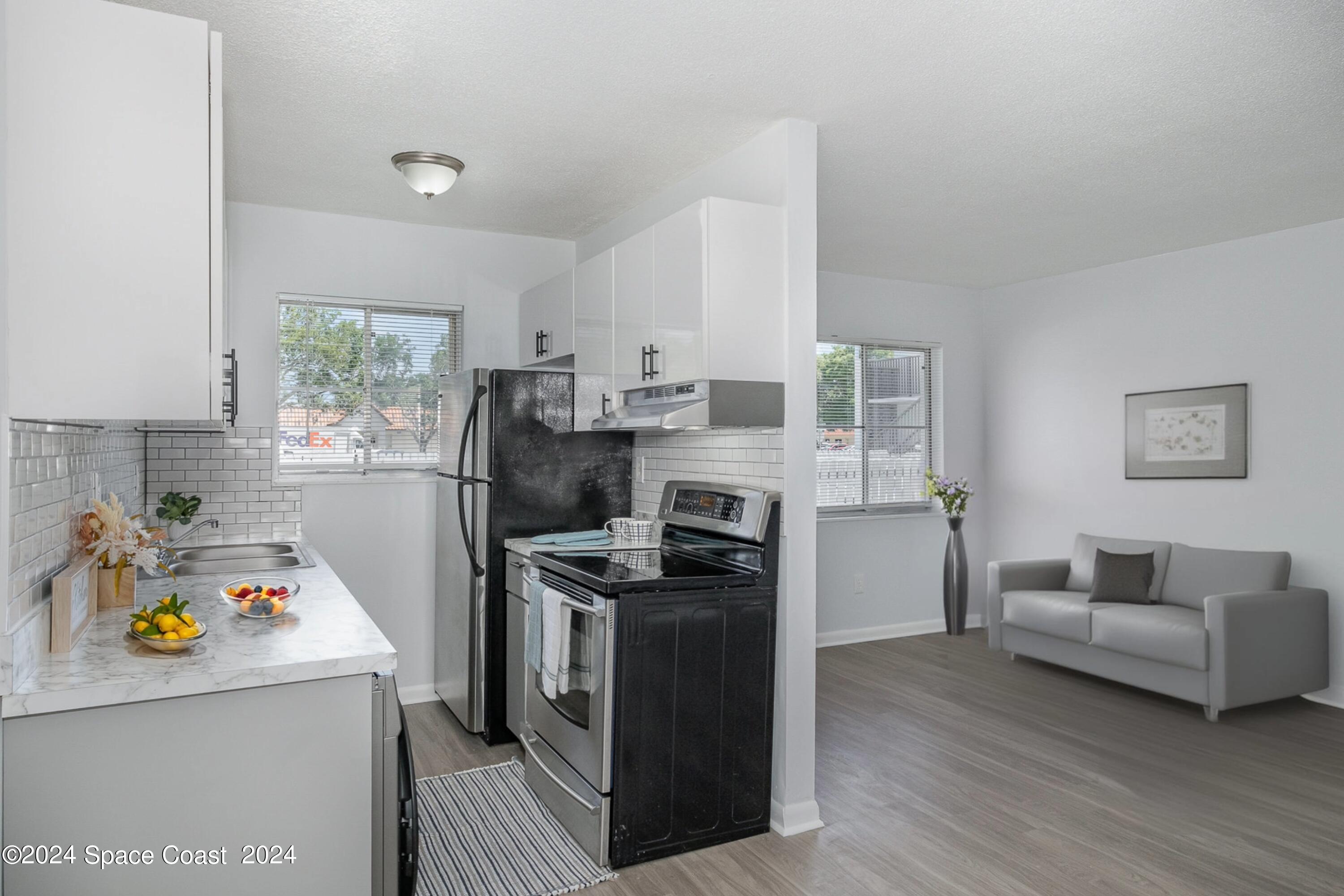 115 Seminole Avenue West, Unit 209 Melbourne, FL 32901 - Photo 4 of 23 a kitchen with stainless steel appliances a stove a refrigerator a sink a stove and white cabinets with wooden floor