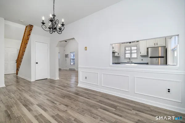 a view of a hallway with wooden floor and chandelier