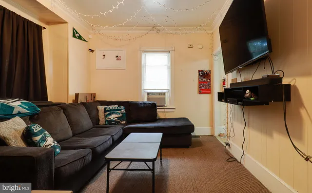 a living room with furniture a flat screen tv and a window