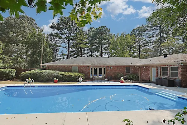a view of swimming pool with outdoor seating and trees in the background