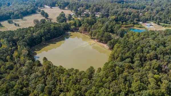 an aerial view of lake residential house with outdoor space and trees all around