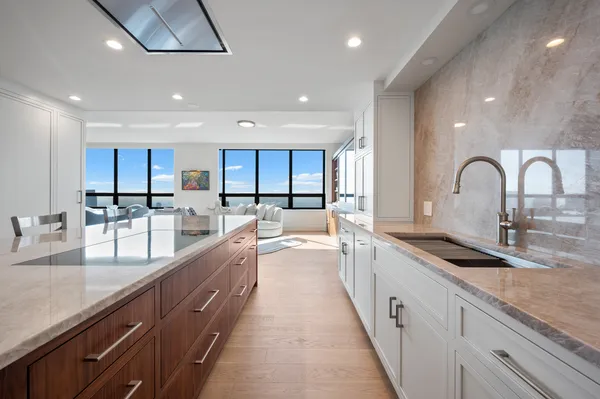 a large kitchen with granite countertop a large counter top a sink stainless steel appliances and cabinets