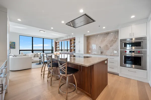 a kitchen with stainless steel appliances kitchen island granite countertop a table chairs and a refrigerator