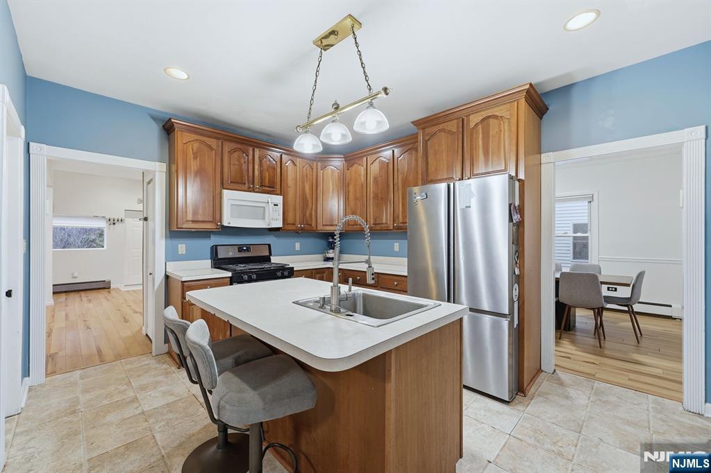 31 West Street Closter, NJ 07624 - Photo 6 of 18 a kitchen with granite countertop a refrigerator a stove a sink dishwasher a dining table and chairs with wooden floor