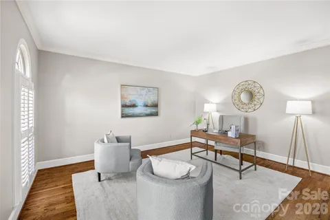 a living room with furniture a clock on wall and a window