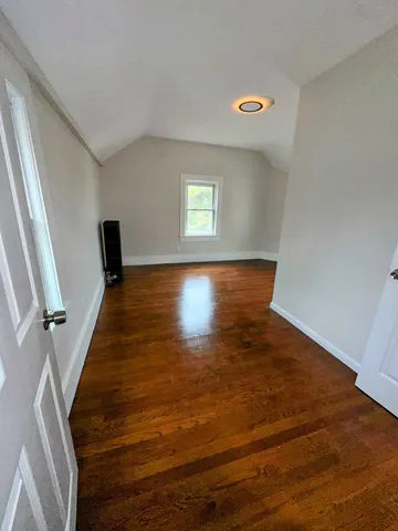 a view of an empty room with wooden floor and stairs