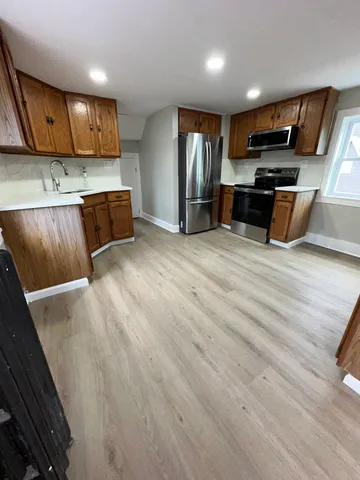 a view of kitchen with stainless steel appliances wooden floor and large window