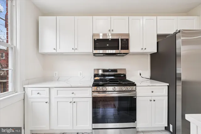 a kitchen with white cabinets and stainless steel appliances