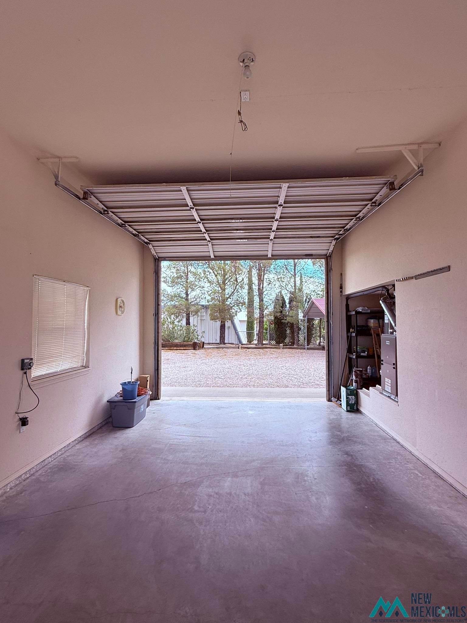 300 Rio Grande Circle Elephant Butte, NM 87935 - Photo 74 of 99 Spacious garage featuring a concrete floor, overhead garage door, interior window with blinds, and exposed ceiling light fixture