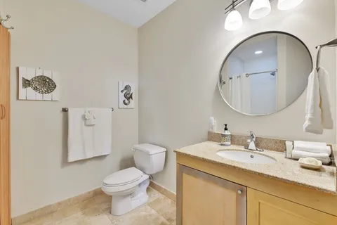 a bathroom with a granite countertop toilet sink vanity and mirror