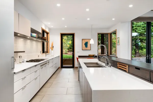 a large kitchen with stainless steel appliances a large counter top a stove a sink and a refrigerator