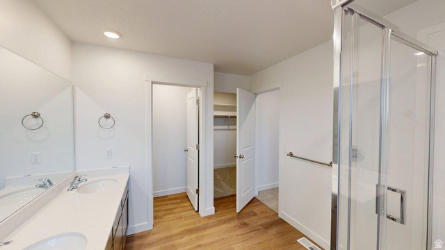 777 Pheasantbrook Drive, Unit 2B Centerville, UT 84014 - Photo 13 of 42 Bathroom featuring a double vanity with integrated sinks, a glass-enclosed shower, wood-finish flooring, and recessed lighting