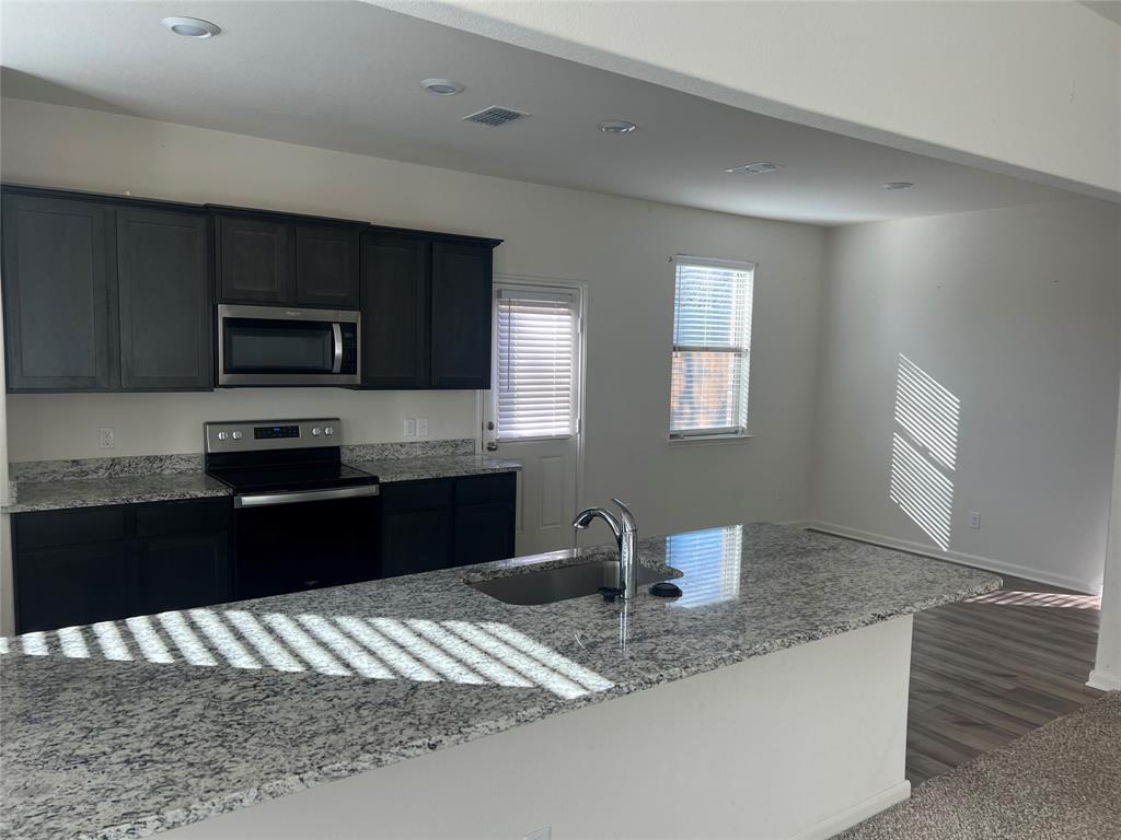 135 Morning Glory Sanger, TX 76266 - Photo 2 of 9 a kitchen with granite countertop stainless steel appliances and wooden cabinets