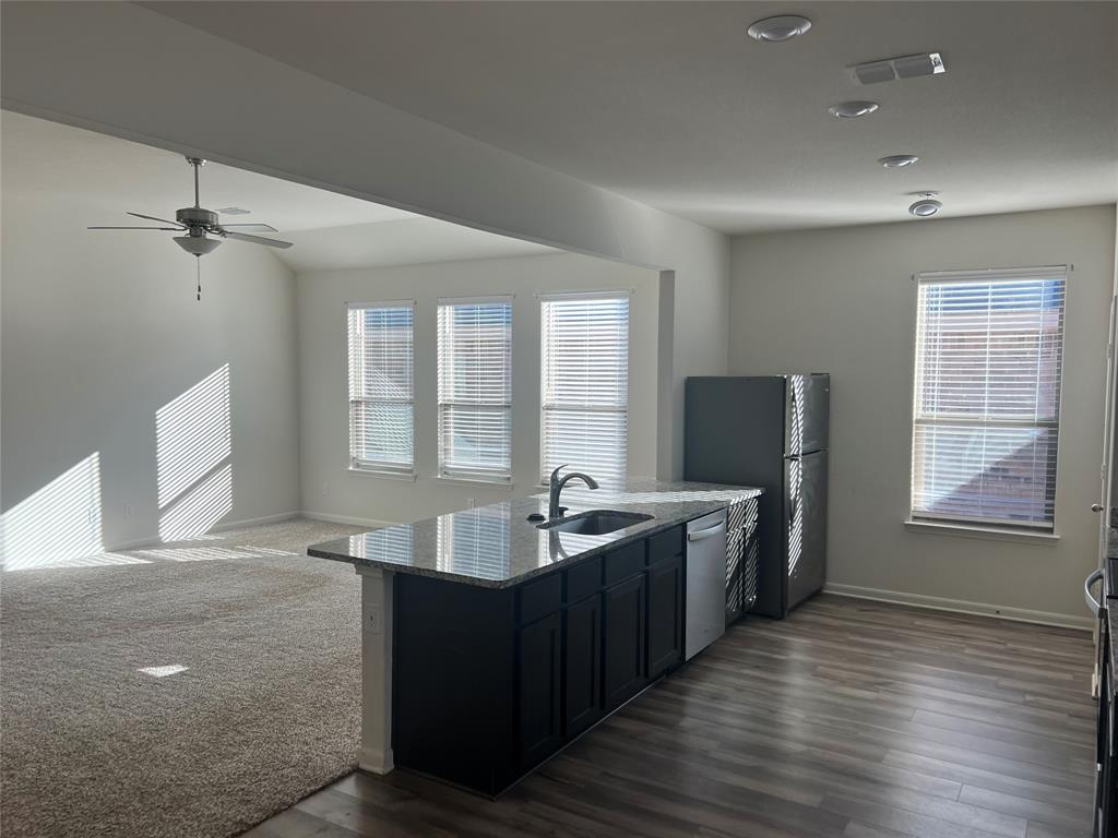 135 Morning Glory Sanger, TX 76266 - Photo 3 of 9 a large living room with stainless steel appliances granite countertop a sink dishwasher a stove and a refrigerator with wooden floor