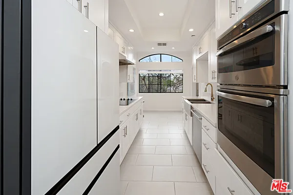 a large white kitchen with granite countertop a stove and a refrigerator