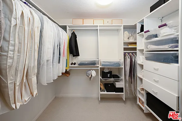 a view of walk in closet with clothes and shoes