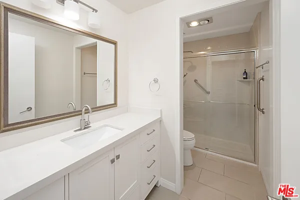 a bathroom with a double vanity sink toilet mirror and shower