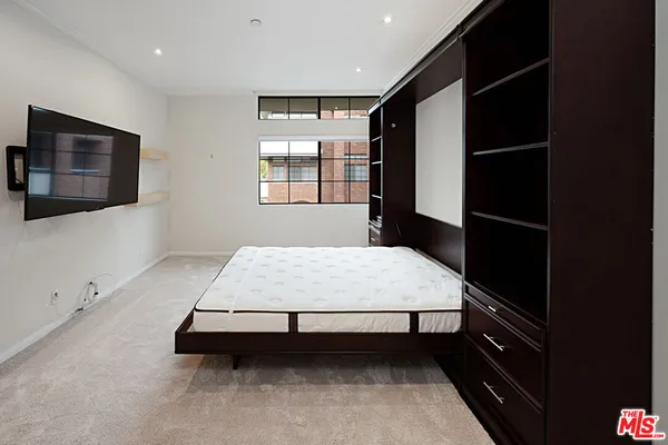 a bedroom with a bed and a flat tv screen on wall