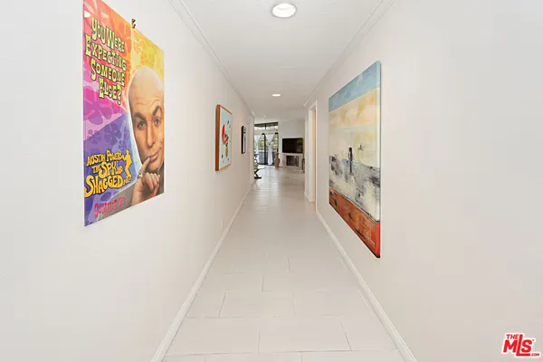 a hallway with painting on the wall and a large window