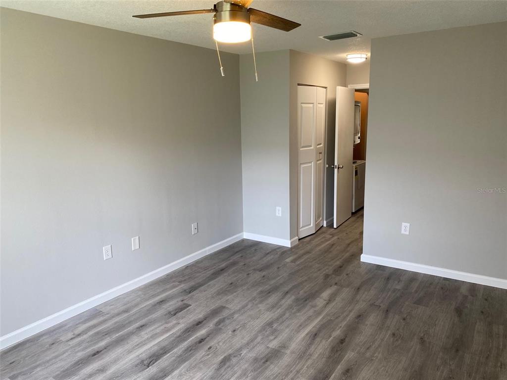 2853 Stillwell Court New Port Richey, FL 34655 - Photo 7 of 15 an empty room with wooden floor and a ceiling fan