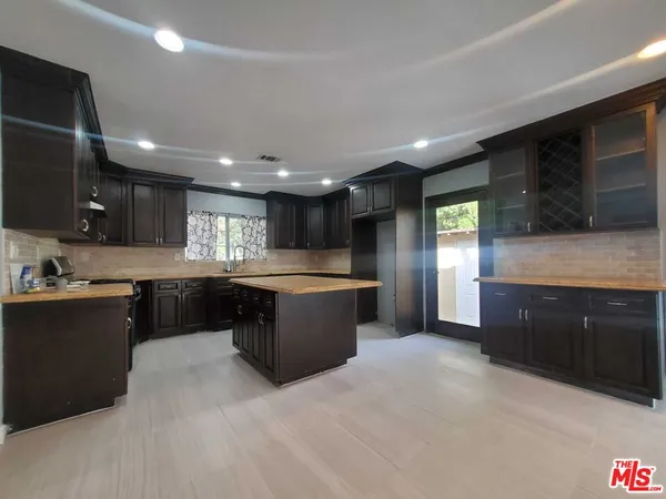 a large kitchen with stainless steel appliances kitchen island granite countertop a stove a sink dishwasher and a refrigerator