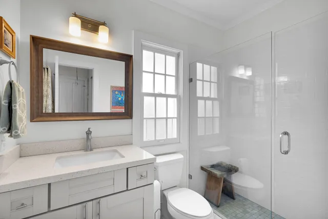 a bathroom with a toilet sink a mirror and next to a window