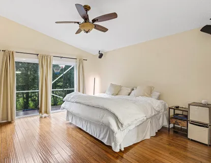 a bedroom with a bed and a large window with wooden floor