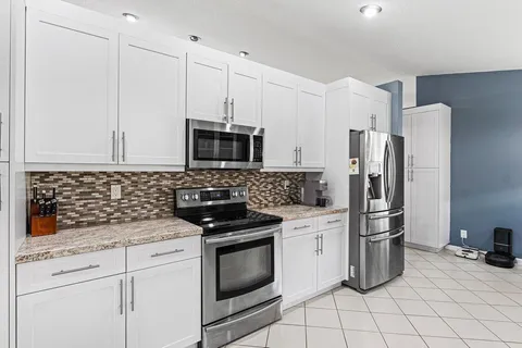 a kitchen with white cabinets and stainless steel appliances