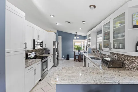 a kitchen with stainless steel appliances granite countertop sink stove top oven and cabinets