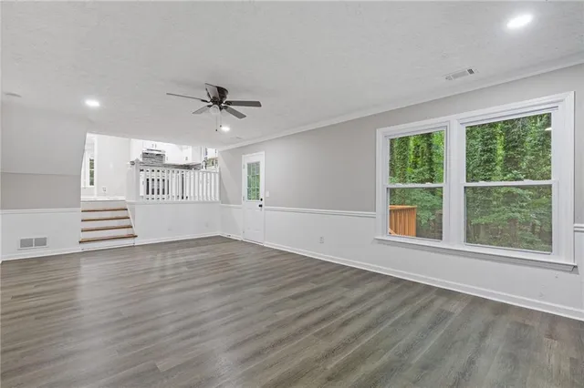 a view of an empty room with a window and wooden floor