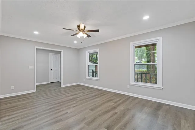 a view of an empty room with a window and wooden floor