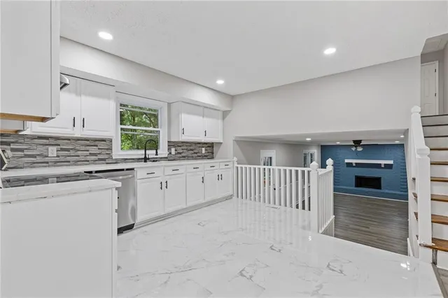 a kitchen with white cabinets a sink a window and stainless steel appliances
