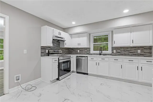 a kitchen with granite countertop white cabinets and stainless steel appliances