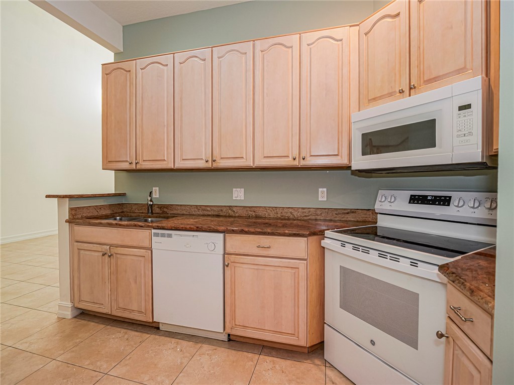 1835 Bridgepointe Circle, Unit 18 Vero Beach, FL 32967 - Photo 9 of 34 a kitchen with granite countertop white cabinets and stainless steel appliances