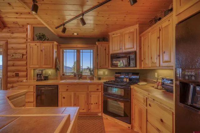 a kitchen with stainless steel appliances granite countertop a sink a stove and wooden cabinets