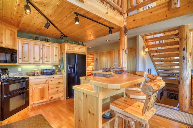 a kitchen with stainless steel appliances kitchen island granite countertop a table chairs in it and wooden floors