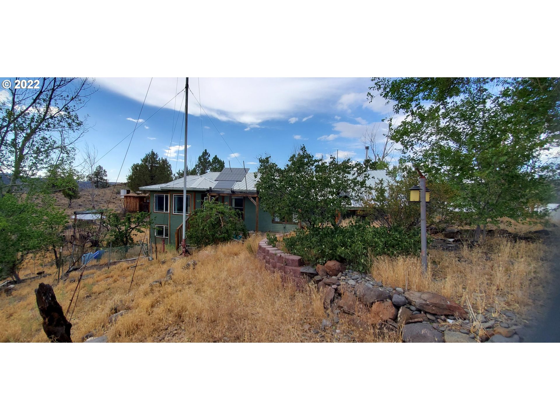 18990 Southeast Doubtful Dirt Road Prineville, OR 97754 - Photo 10 of 32 a view of a backyard with table and chairs under an umbrella