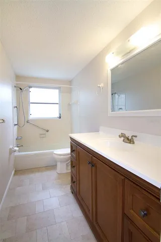 a spacious bathroom with a granite countertop sink a toilet and a bathtub