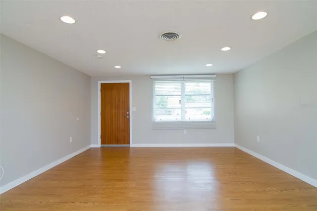 an empty room with wooden floor and windows